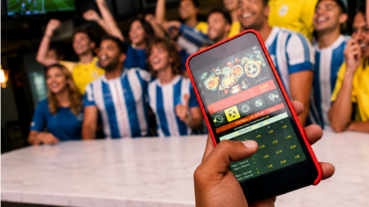Aficionados celebrando un partido mientras consultan estad&iacute;sticas en un m&oacute;vil
